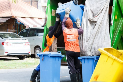 Workers using safe lifting techniques during rubbish removal